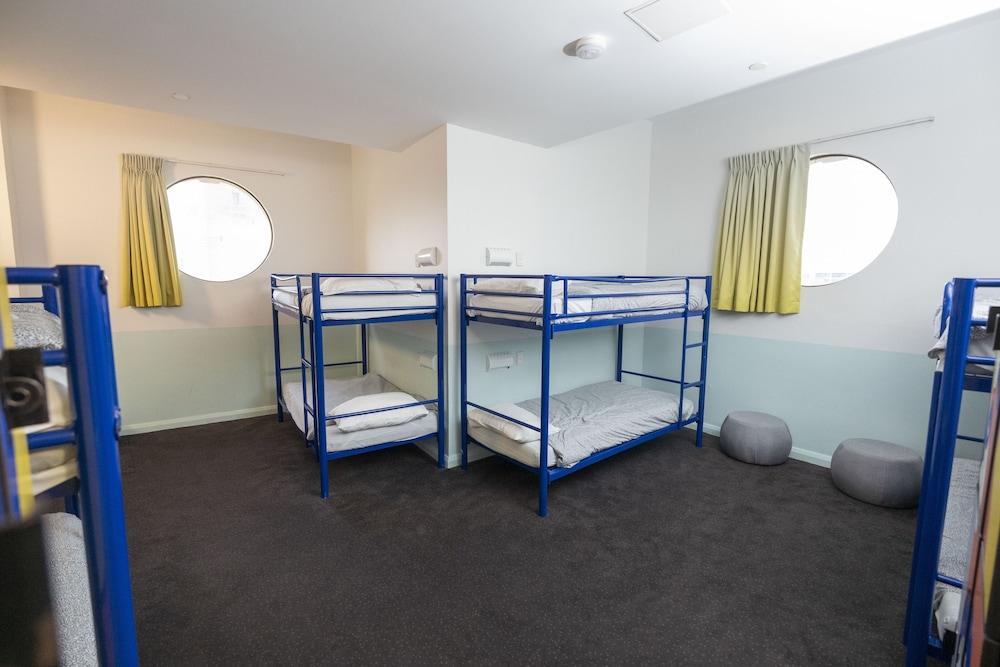 Yha Sydney Central Exterior photo The photo shows a dormitory-style room featuring two sets of blue metal bunk beds. The beds are unmade, with mattresses visible. The room has two round windows adorned with light-colored curtains, allowing natural light to illuminate the space. The f