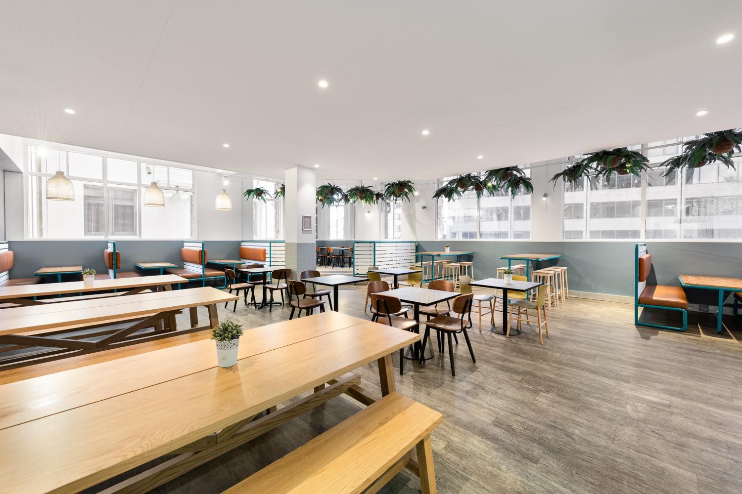 Yha Sydney Central Exterior photo The photo shows a spacious and modern dining or café area. It features a variety of seating arrangements, including long wooden tables with benches and smaller tables with chairs. The space is well-lit with natural light coming through large windows 
